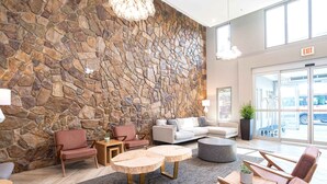Un hall d’entrée aux murs en pierre, doté d’espaces pour s’asseoir et d’une grande fenêtre.