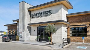 Un bâtiment avec une enseigne indiquant « MOXIES » et une entrée accessible aux personnes en fauteuil roulant.