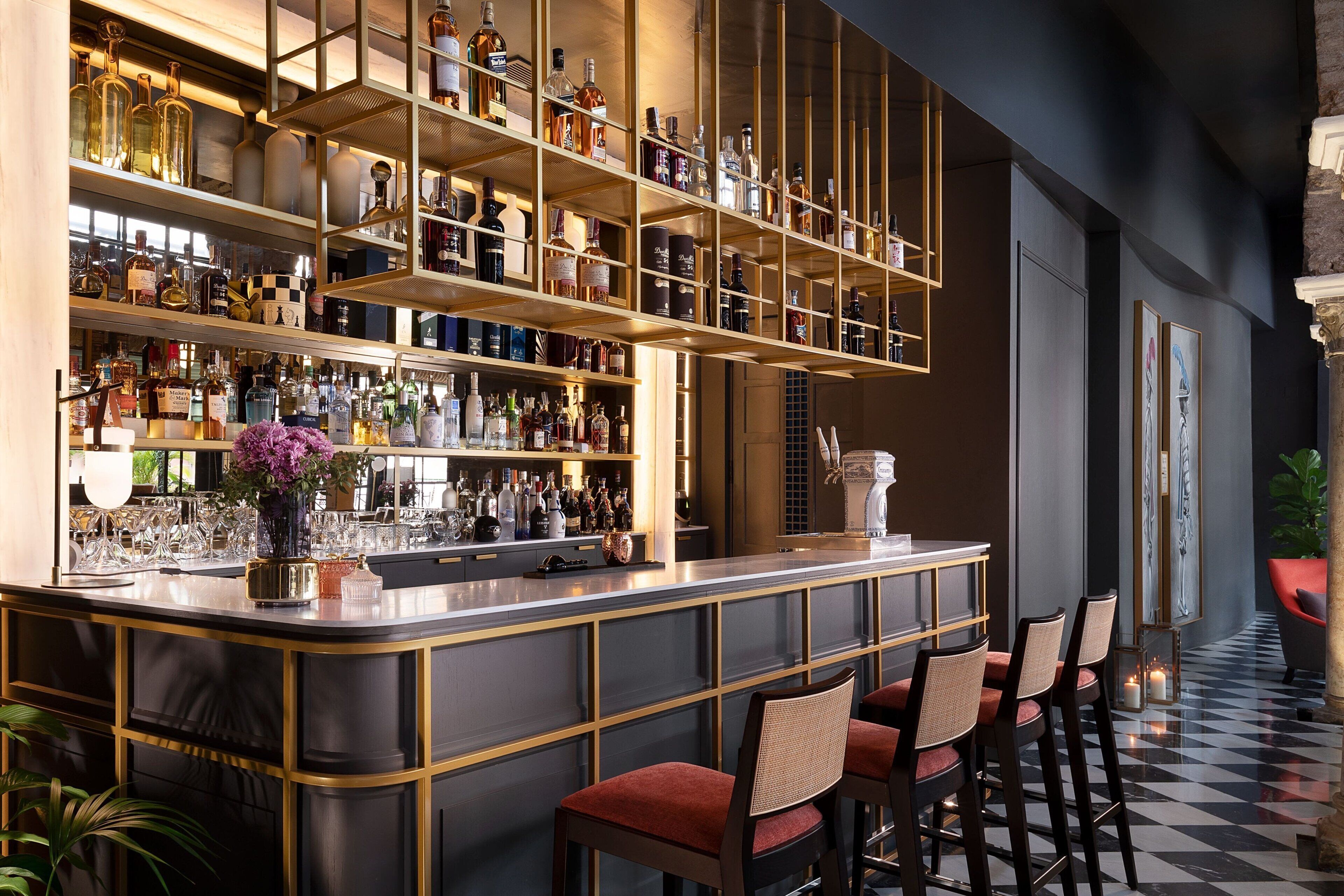 A bar area with shelves of bottles, a bar counter, and seating.