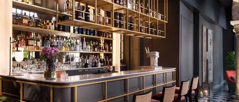 A bar area with shelves of bottles, a bar counter, and seating.