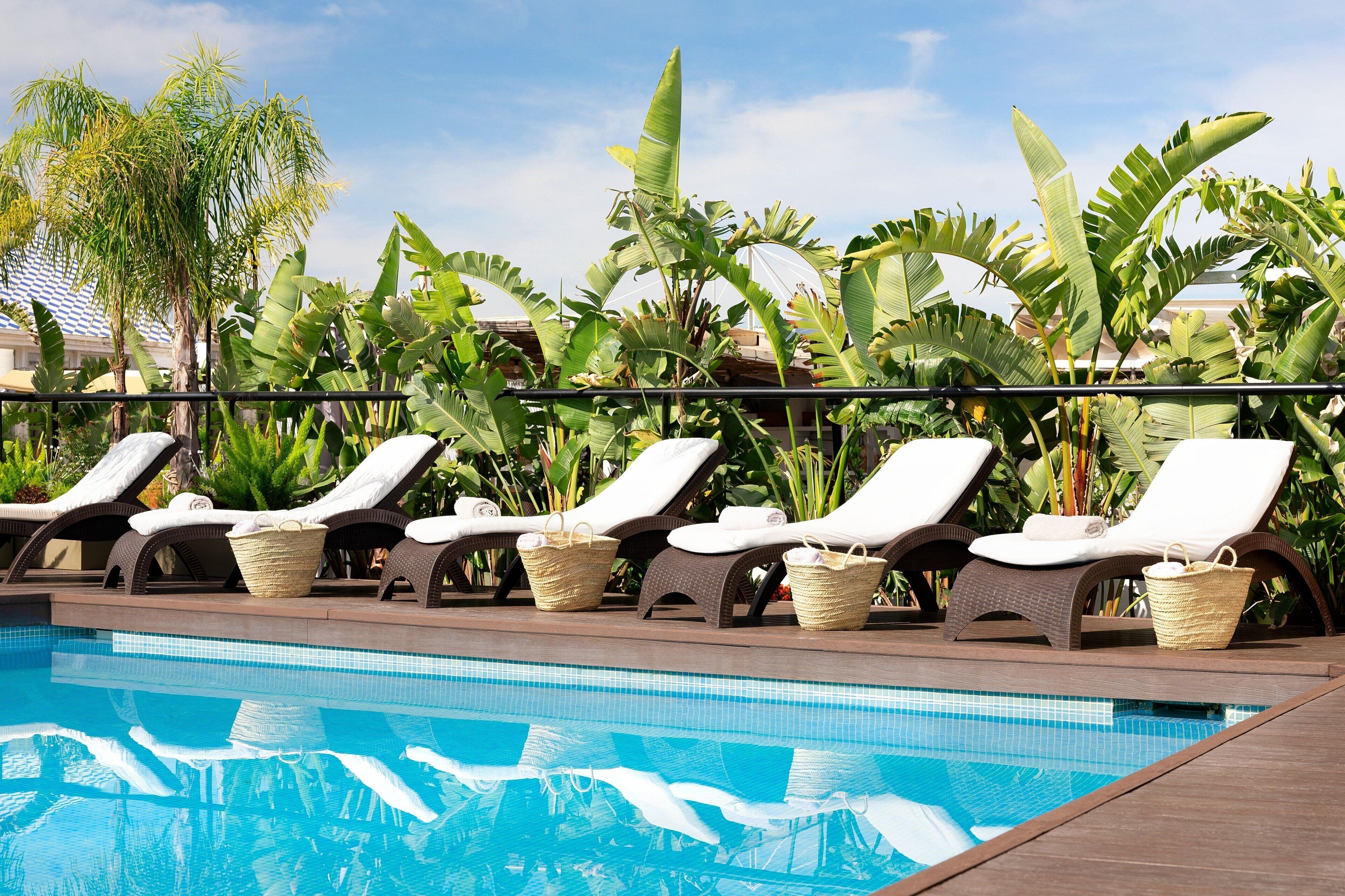 Een buitenzwembad, parasols bij het zwembad en ligstoelen