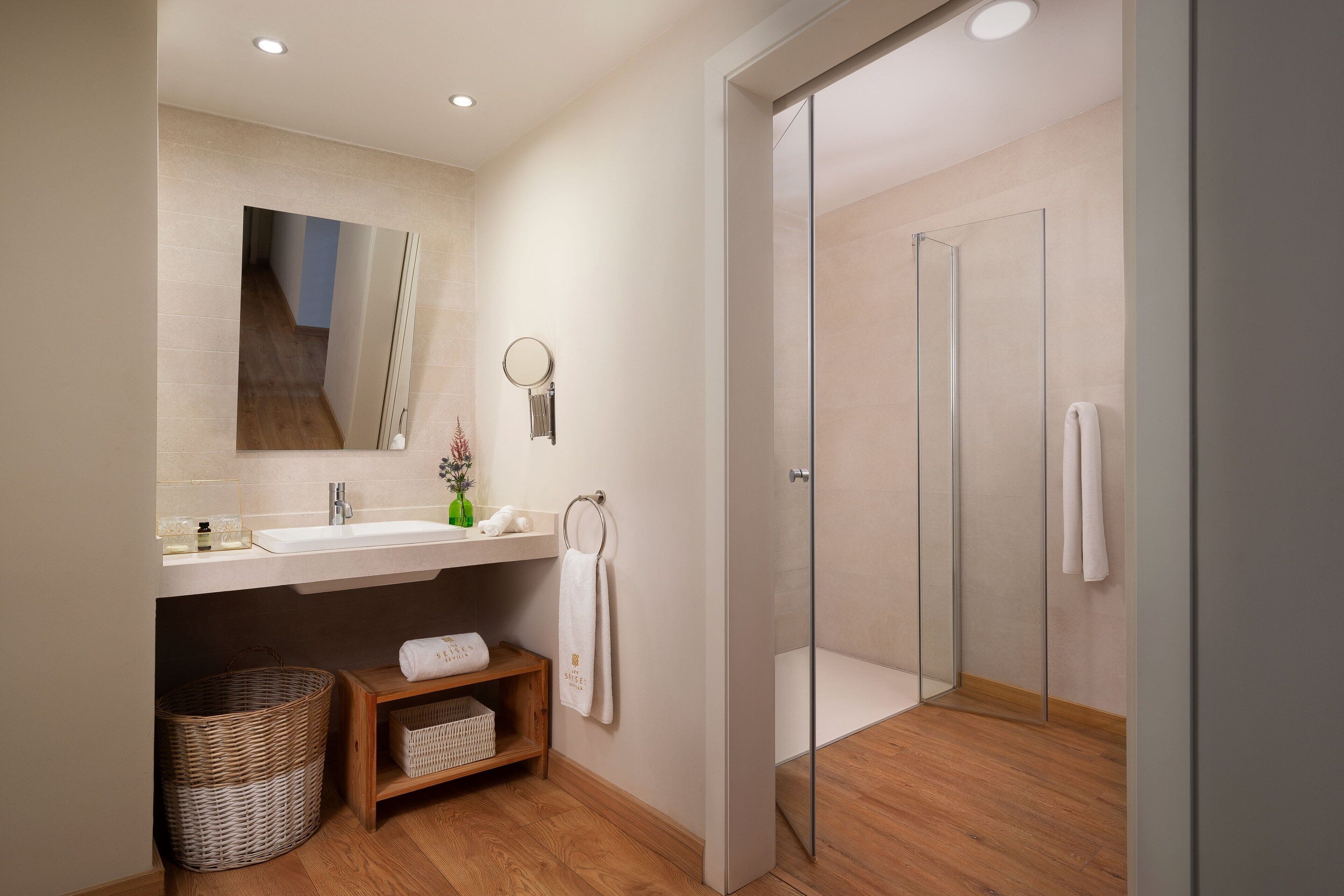 A modern bathroom with a sink, mirror, and glass shower enclosure.