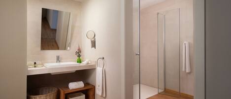 A modern bathroom with a sink, mirror, and glass shower enclosure.
