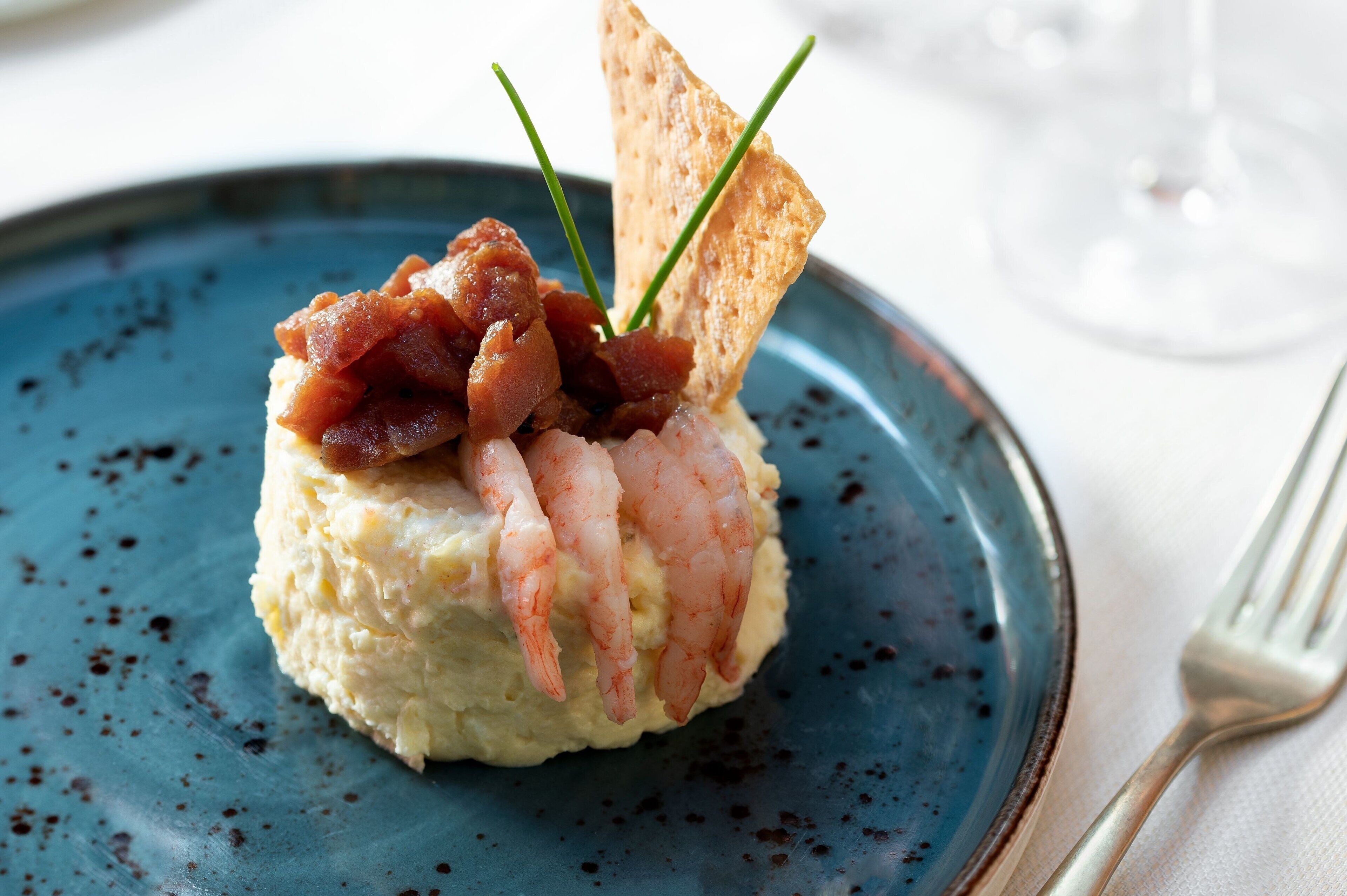 Um prato com prato de frutos do mar, um garfo e um copo de vinho.