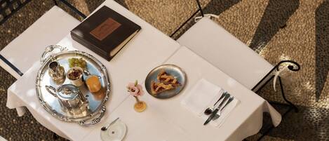 Una mesa de comedor dispuesta con una bandeja de plata, un libro y un plato con comida.