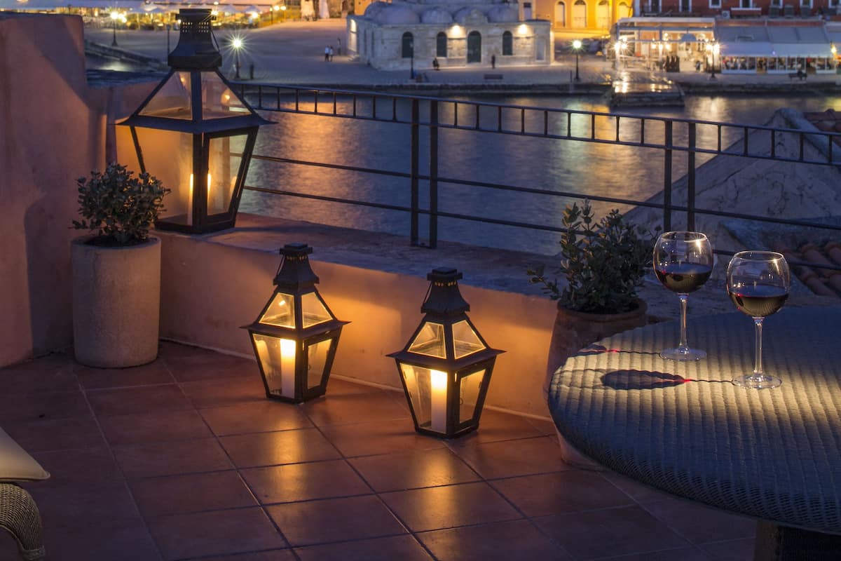 Eine Terrasse mit Laternen, Blick auf die Stadt und ein Gewässer.