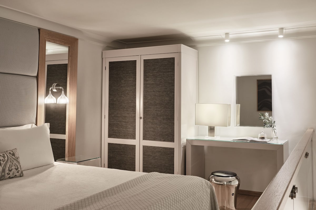 Ein modernes Schlafzimmer mit Bett, Kleiderschrank, Schreibtisch und Spiegel.