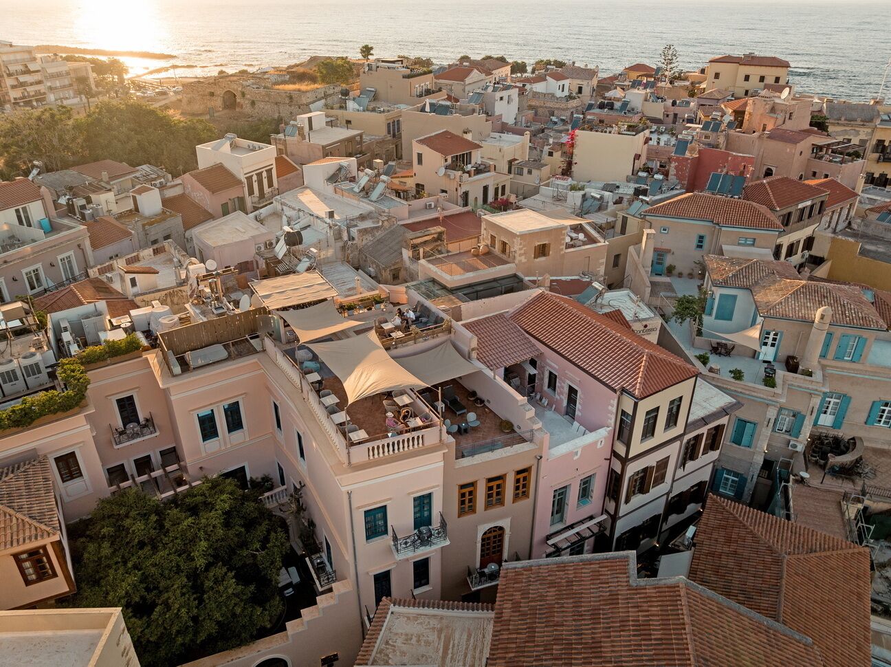 A coastal town with terracotta-roofed buildings, balconies, and a view of the sea.