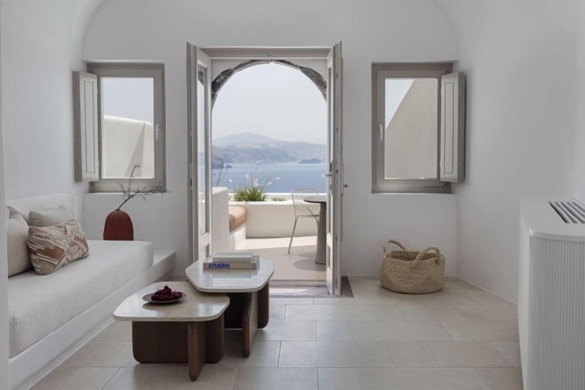 Un interior moderno con un sofá, una mesita, vistas al exterior por una puerta abierta y un radiador.
