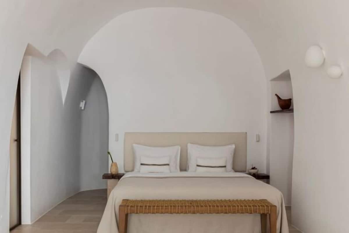 A bedroom with a bed, nightstands, a bedside table, and a wall-mounted shelf.
