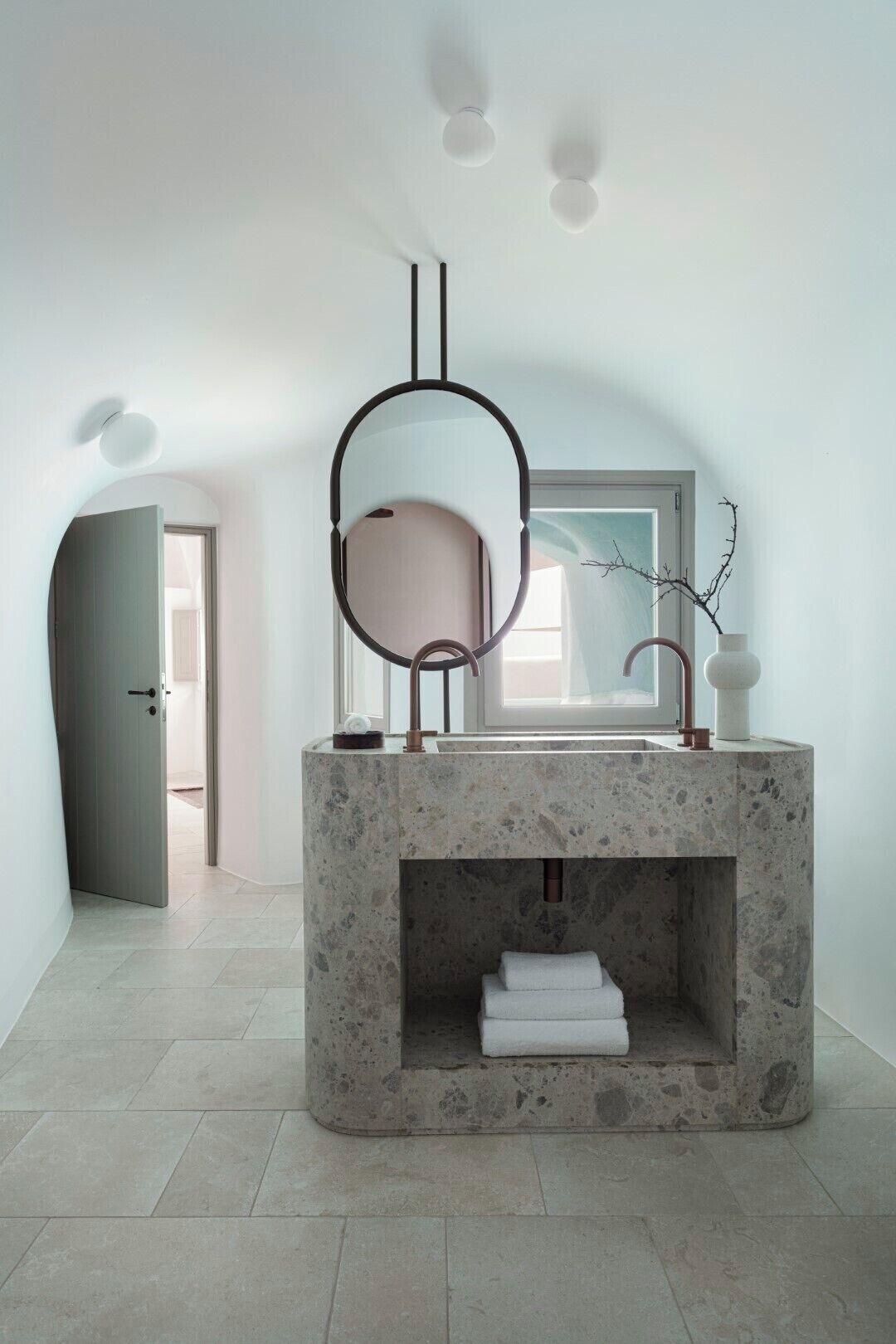 Un baño moderno con un lavamanos de mármol independiente, un espejo grande y un perchero para toallas.