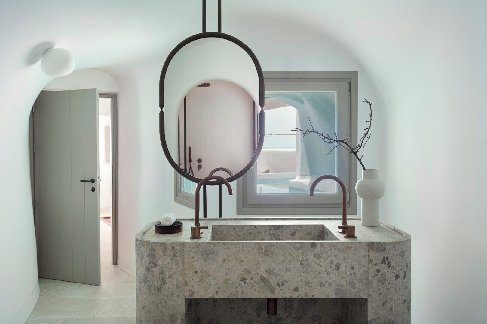 Un baño con un espejo grande, un lavamanos y una ventana.