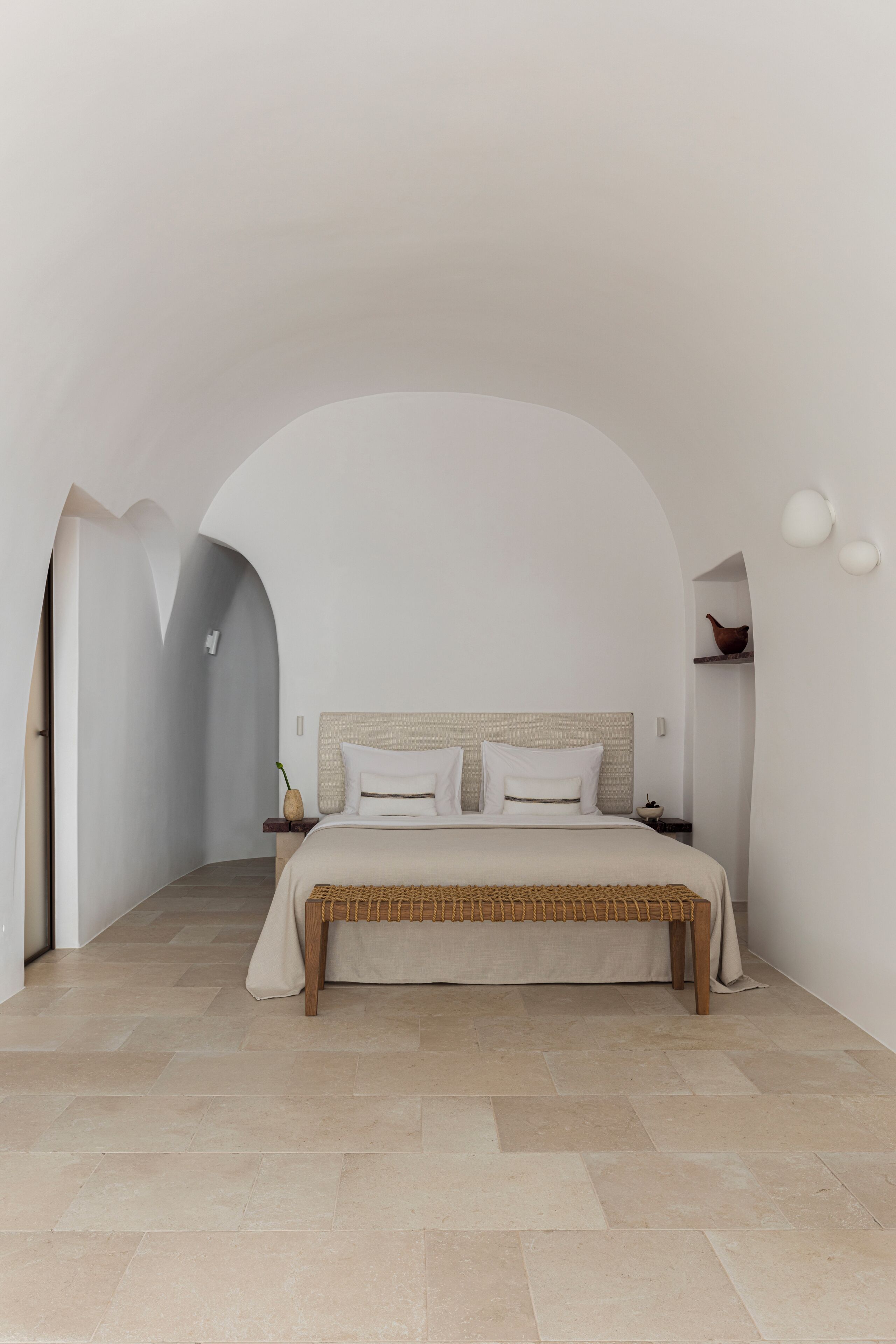 A bedroom with a bed, a nightstand, and a wall-mounted light fixture.