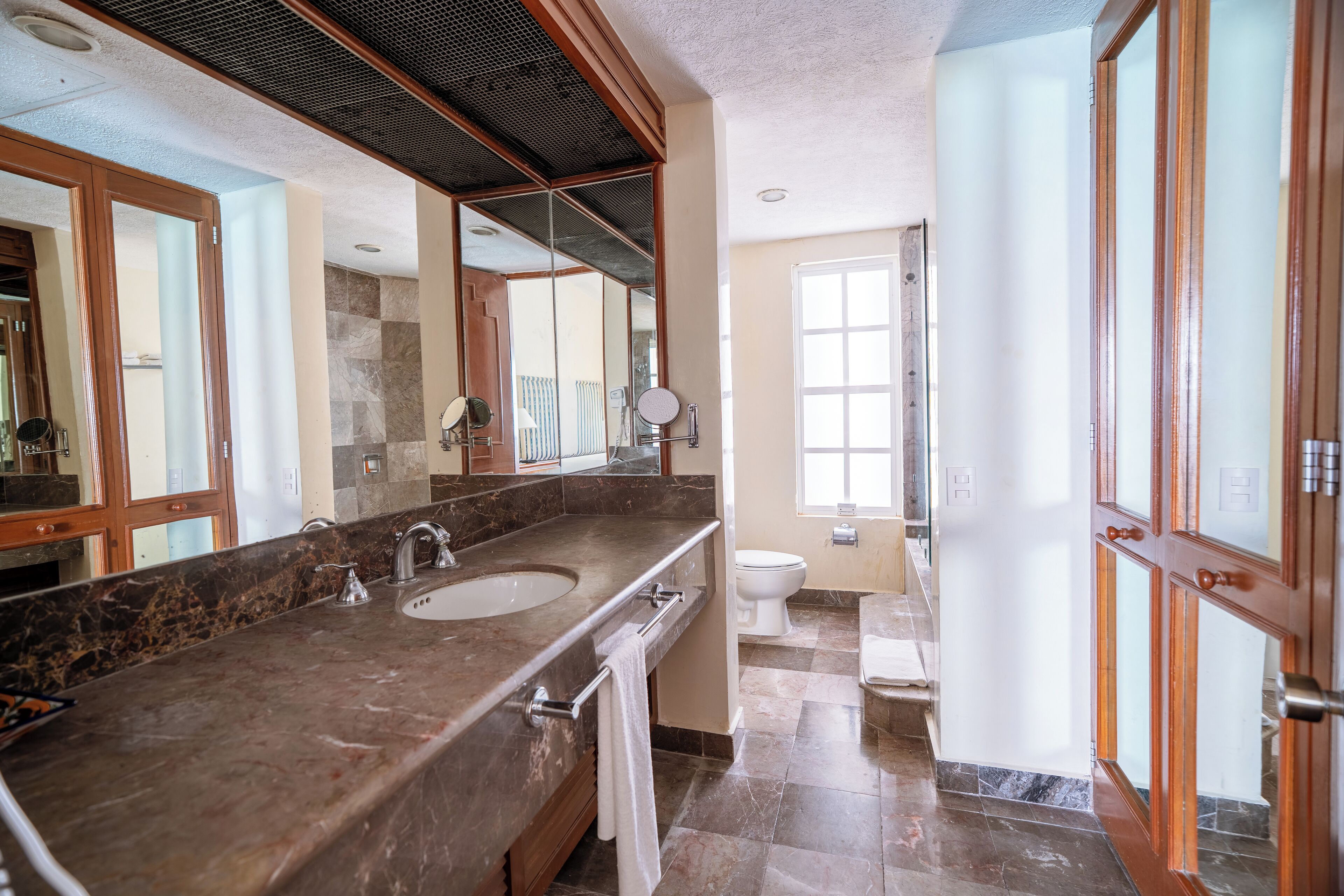 Un baño moderno con un lavabo grande de mármol, un inodoro y un espejo.