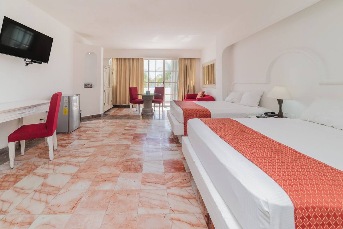 Een hotelkamer met een bed, een bureau, een televisie en een zithoek met stoelen.