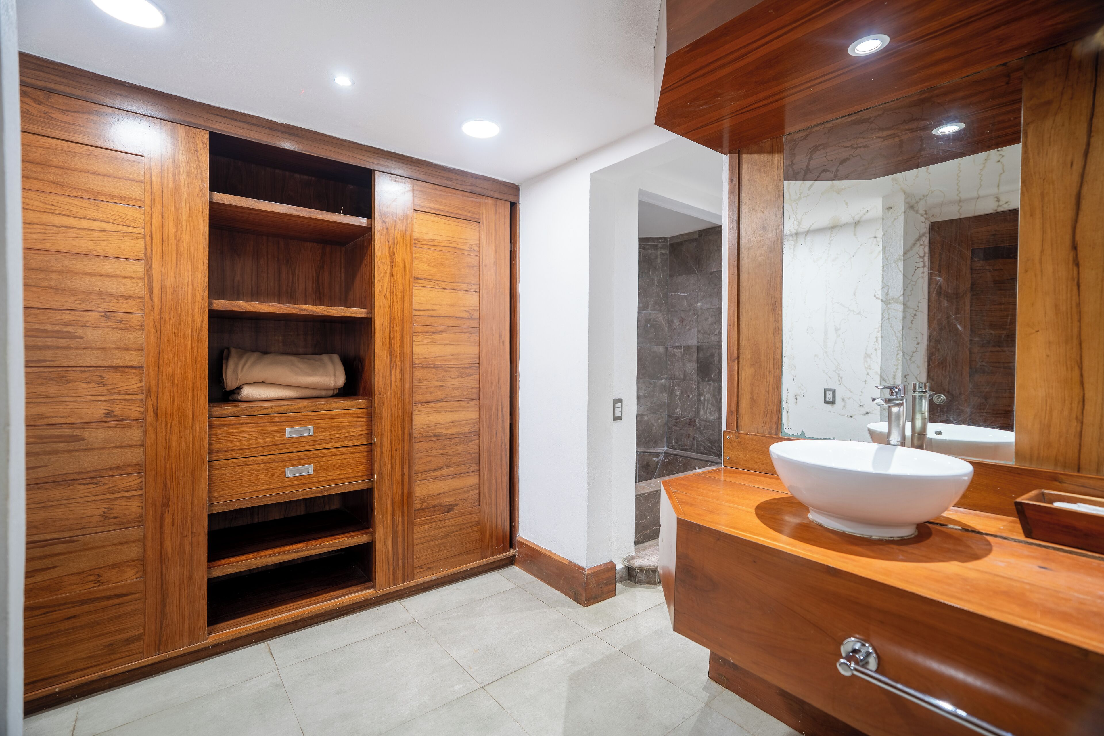 A modern bathroom with a wooden vanity, a large mirror, and a built-in shower area.