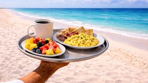 Bandeja con alimentos para el desayuno y una taza de café en la playa.