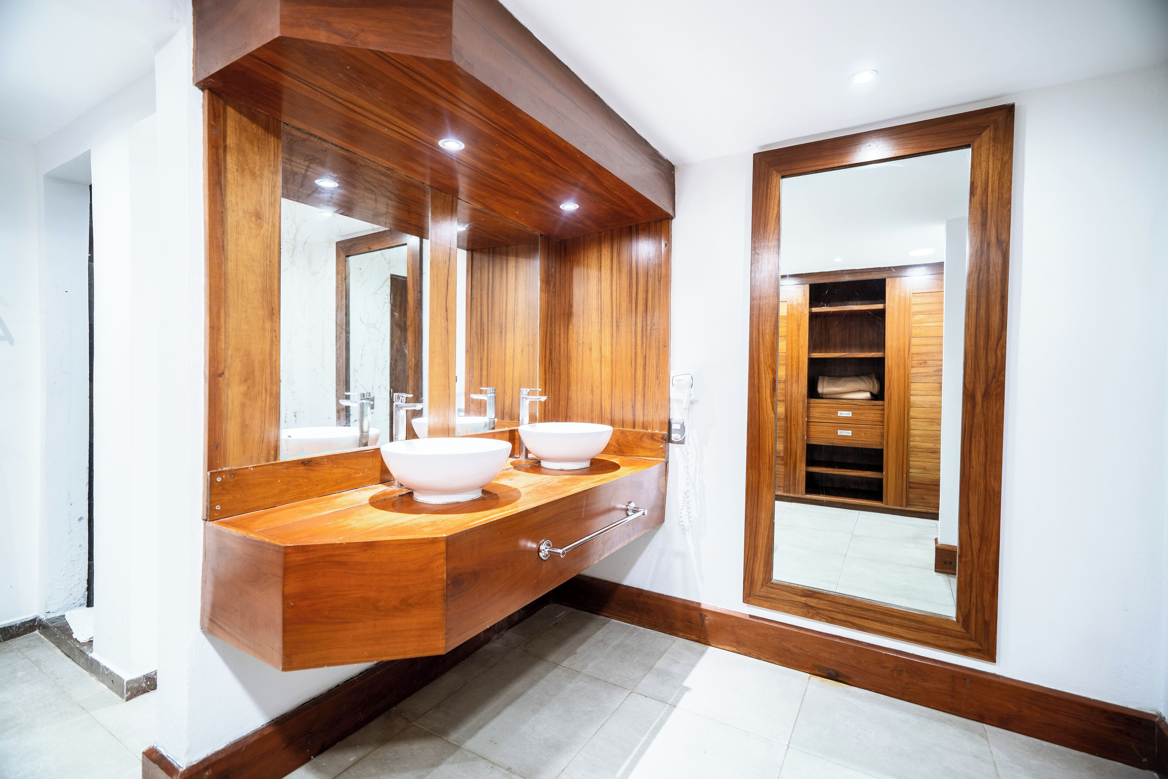 A modern bathroom with wooden vanity, dual sinks, and a large mirror.