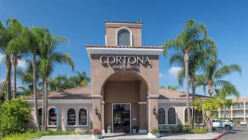 A hotel with a sign reading 'CORTONA INN & SUITES' and a bell tower.