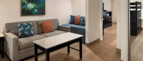 A modern living room with a sofa, a coffee table, and a painting on the wall.