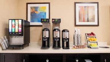 A self-service beverage station with multiple dispensers, a coffee machine, and a fruit display.