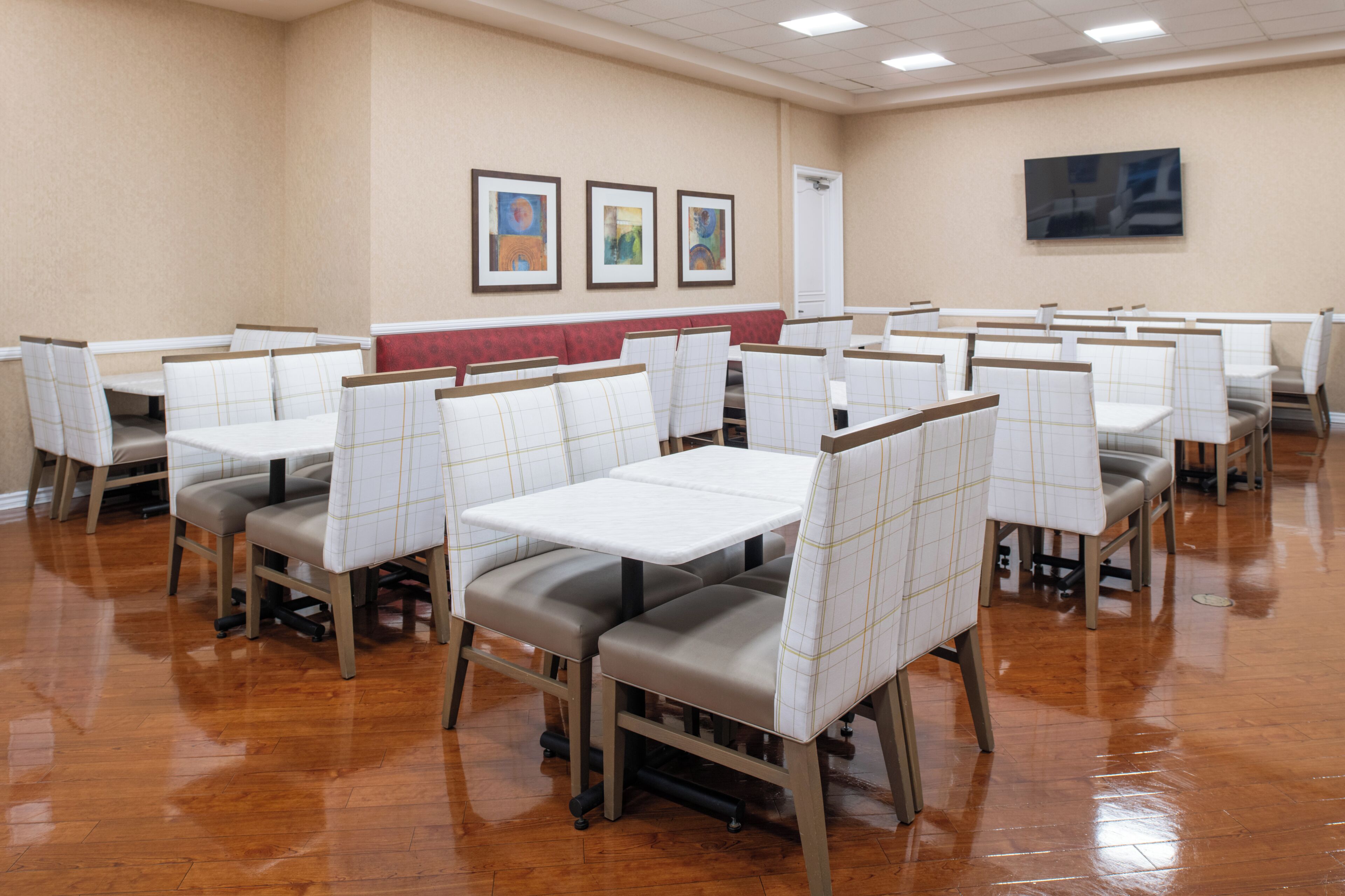 A dining area with booths and tables, wooden flooring, and artwork on the walls.