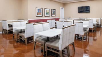 A dining area with booths and tables, wooden flooring, and artwork on the walls.