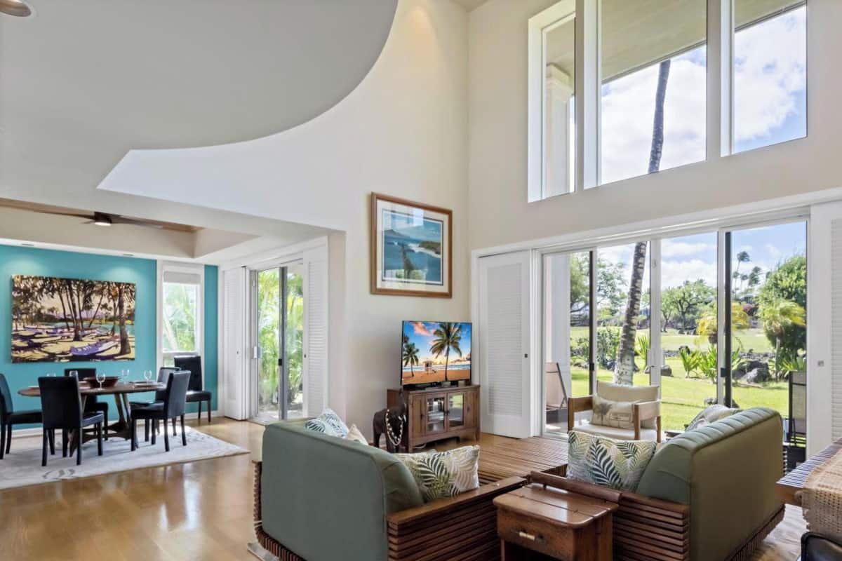 A spacious living area with a dining table, sofas, and a TV.