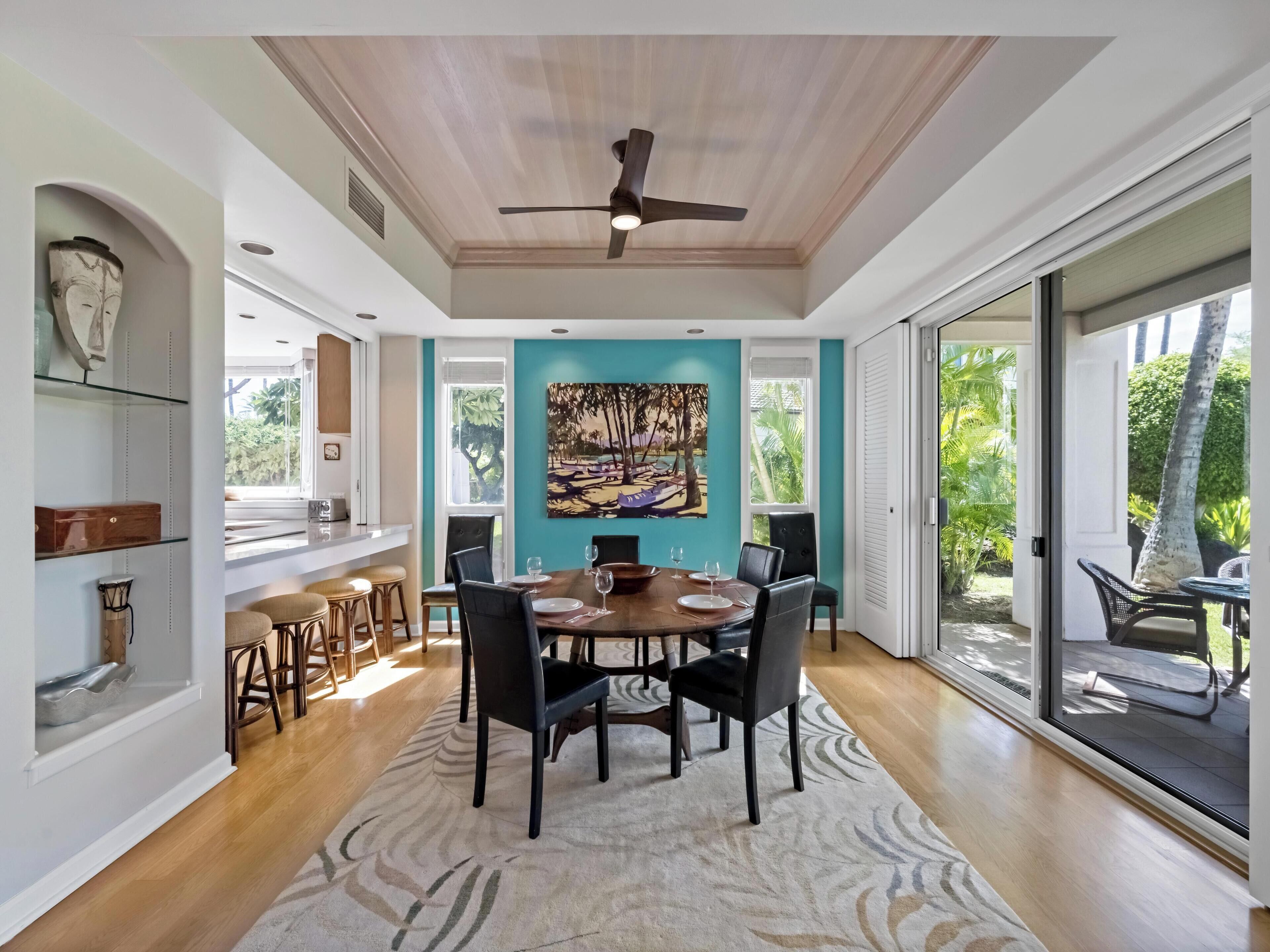 A spacious dining area with a large table, chairs, and a ceiling fan.