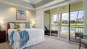 Een slaapkamer met een groot bed, uitzicht op een golfbaan en een schuifdeur naar een balkon.