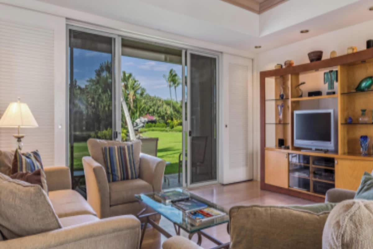 A modern living room with a sofa, armchairs, a coffee table, and a TV stand with a flat-screen TV.