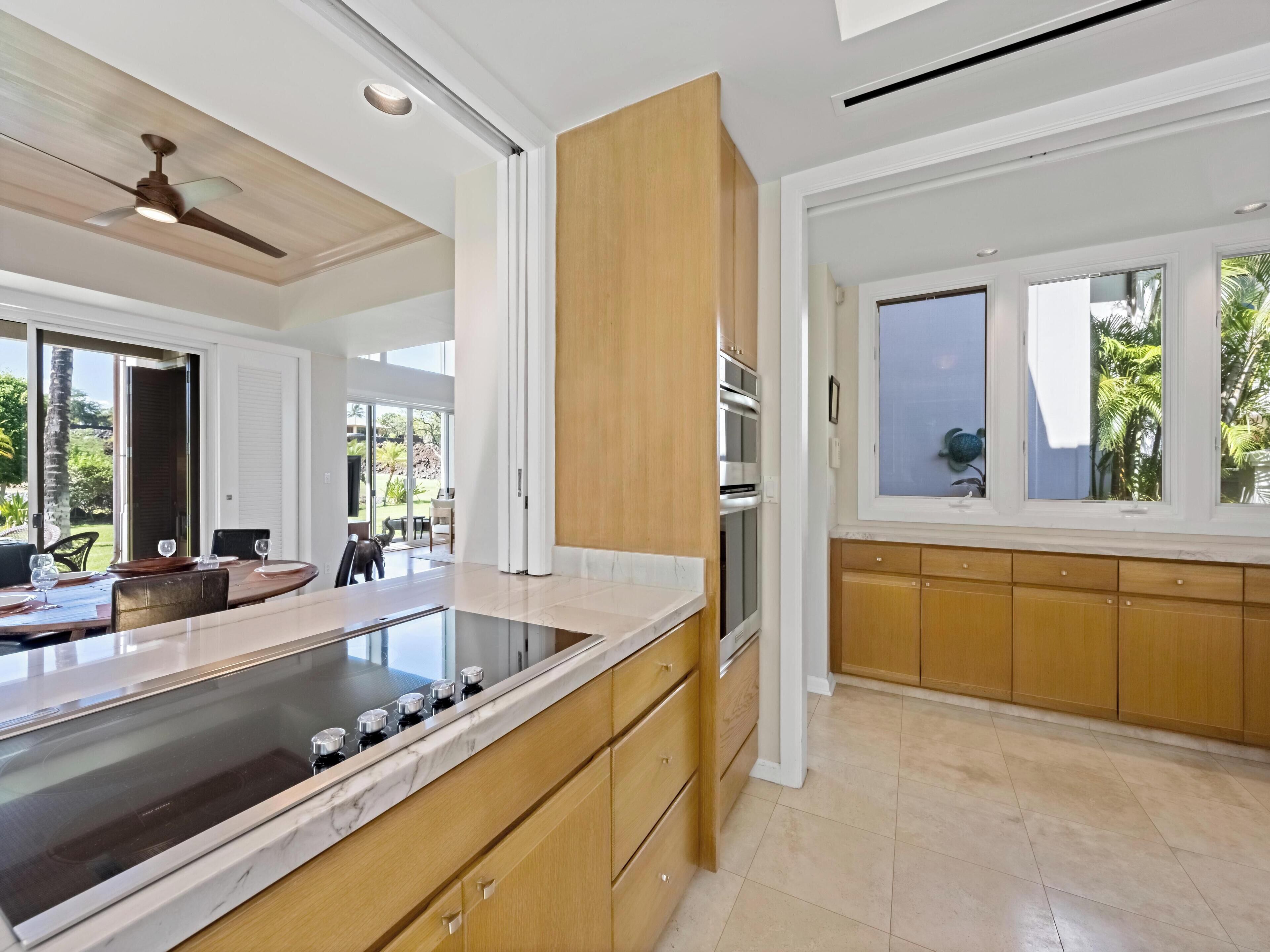 Una cocina moderna con una isla grande, armarios de madera y vistas al exterior.