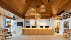 A reception area with a wooden reception desk, three hanging wicker lamps, and a reception sign. - BreakFree Aanuka Beach Resort (Coffs Harbour)