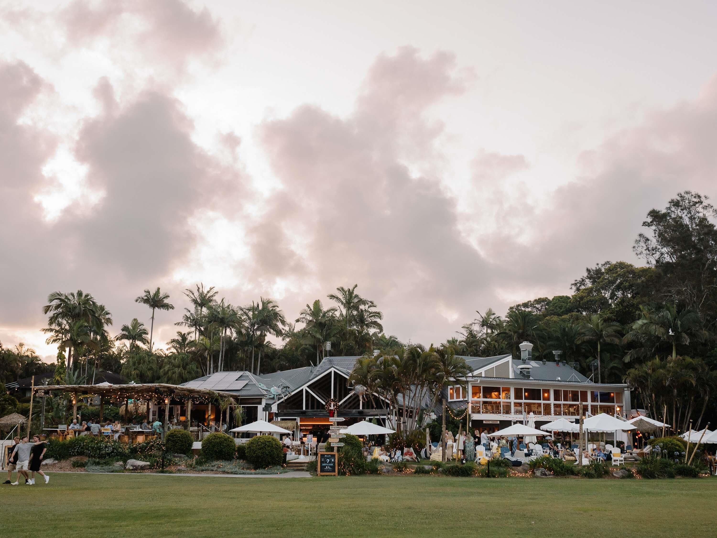 A resort with outdoor seating, palm trees, and a building with large windows.