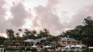 A resort with outdoor seating, palm trees, and a building with large windows.