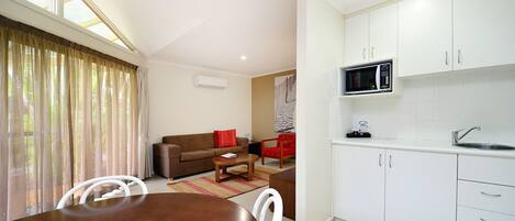 Un espace de vie compact comprenant un coin repas, une kitchenette et un coin salon.