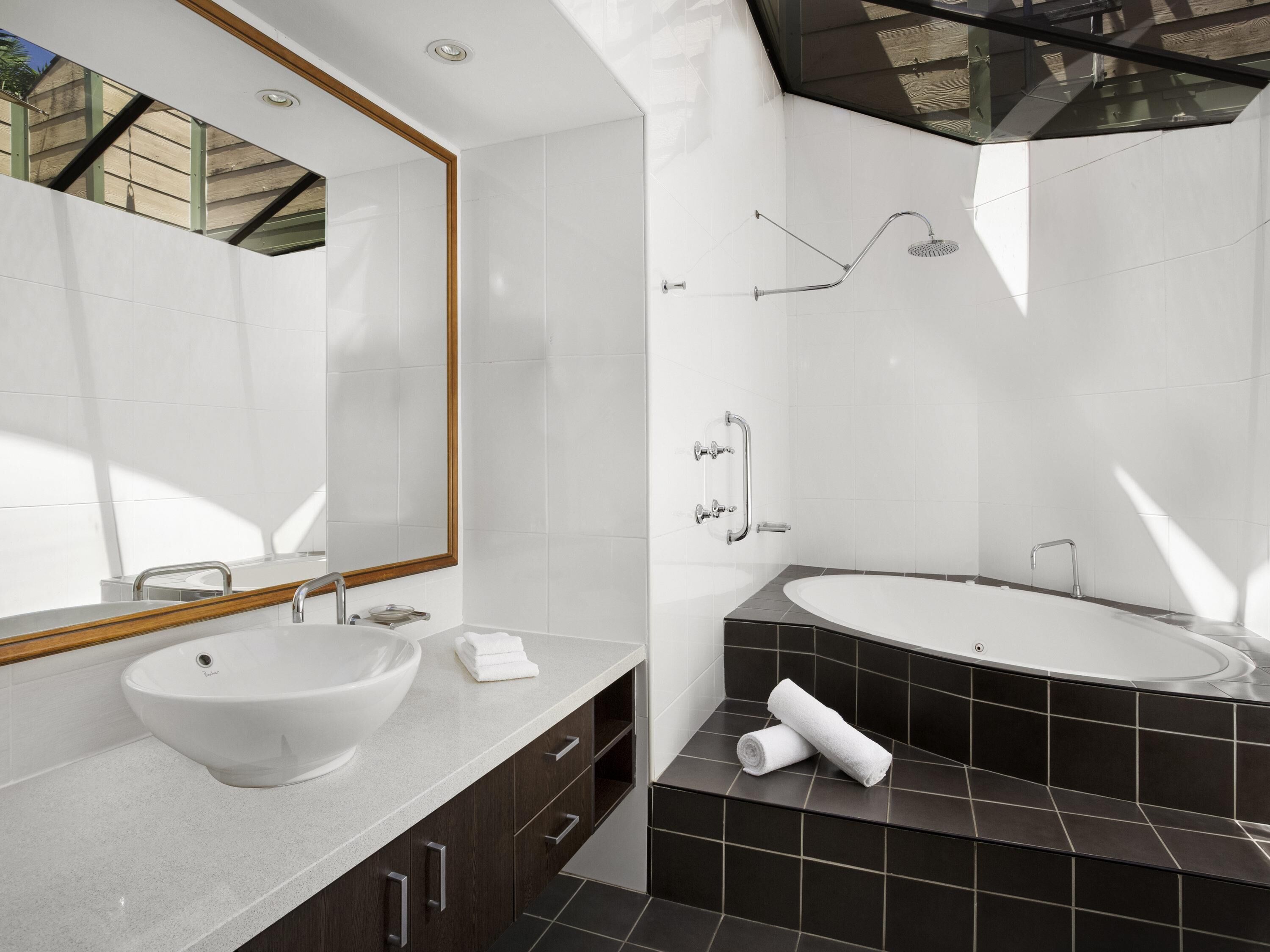 A modern bathroom with a large sink, a bathtub, and a shower.