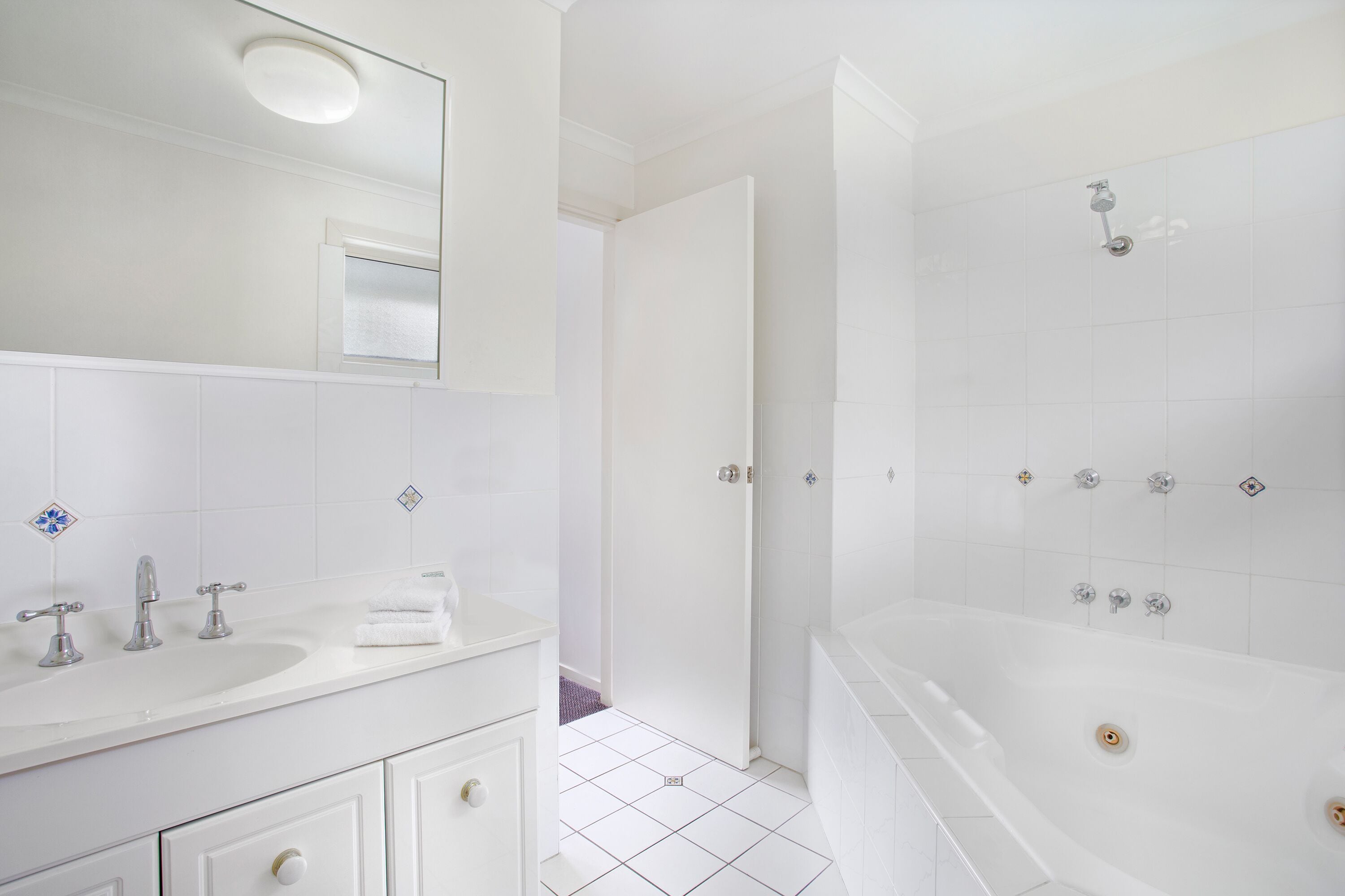Une salle de bain moderne avec un lavabo blanc, un miroir et une baignoire.