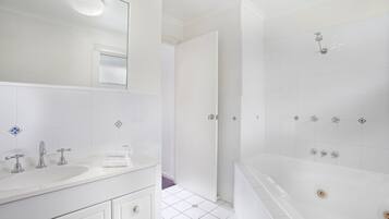 Une salle de bain moderne avec un lavabo blanc, un miroir et une baignoire.