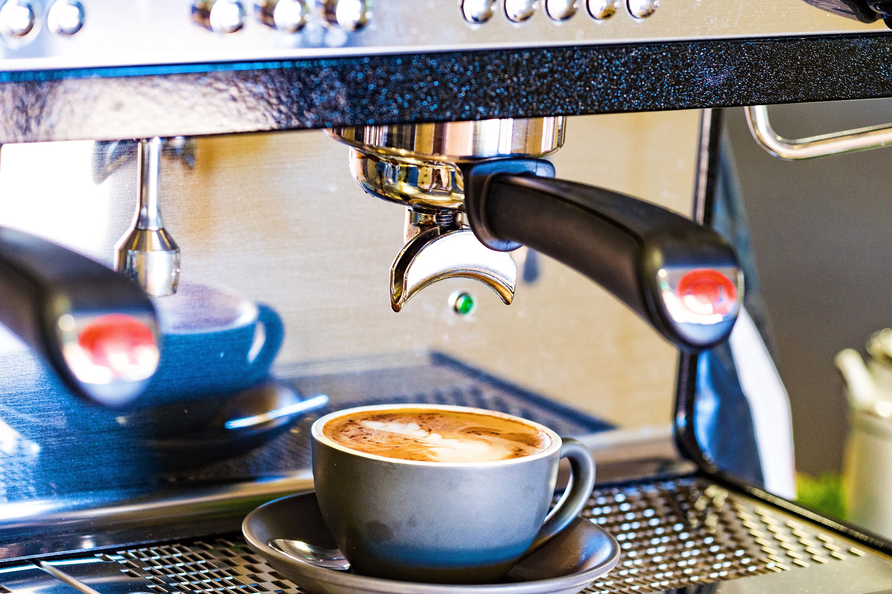 Eine Kaffeemaschine gibt Espresso in eine Tasse ab.