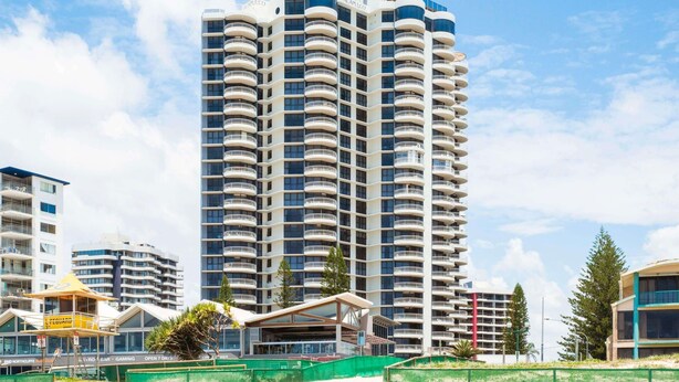 A high-rise hotel with multiple balconies, a lifeguard tower, and a beach in the foreground. - Breakfree Acapulco (Surfers Paradise)