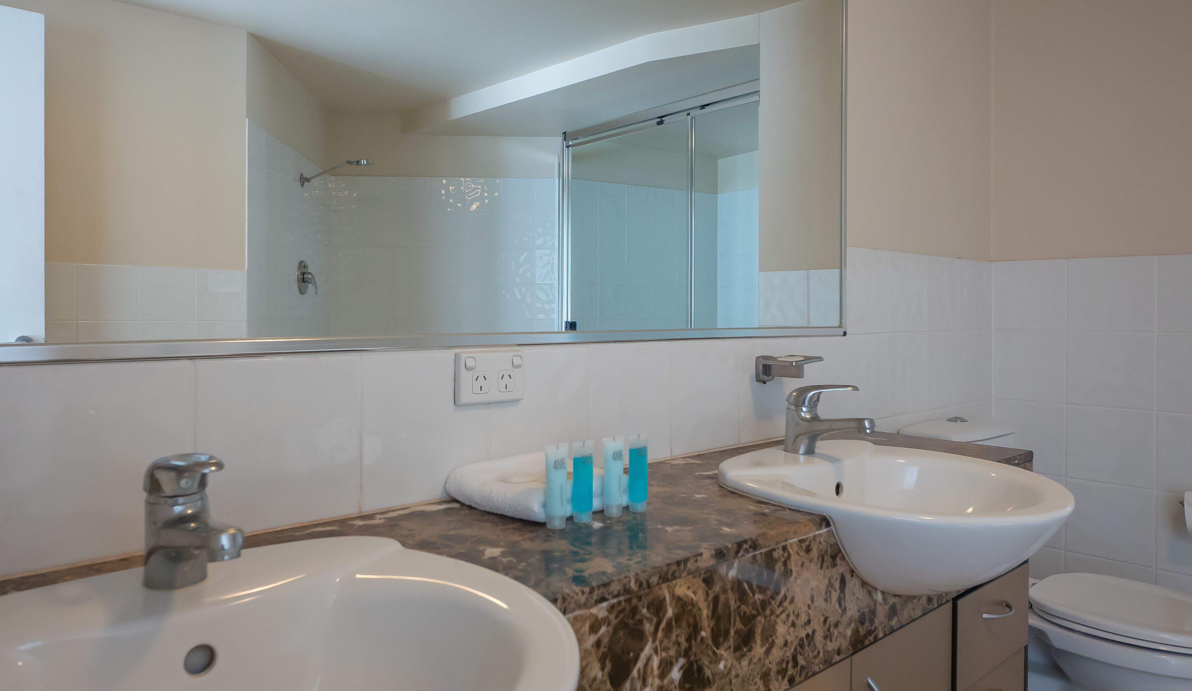 Un baño con dos lavabos, un espejo y una ducha.