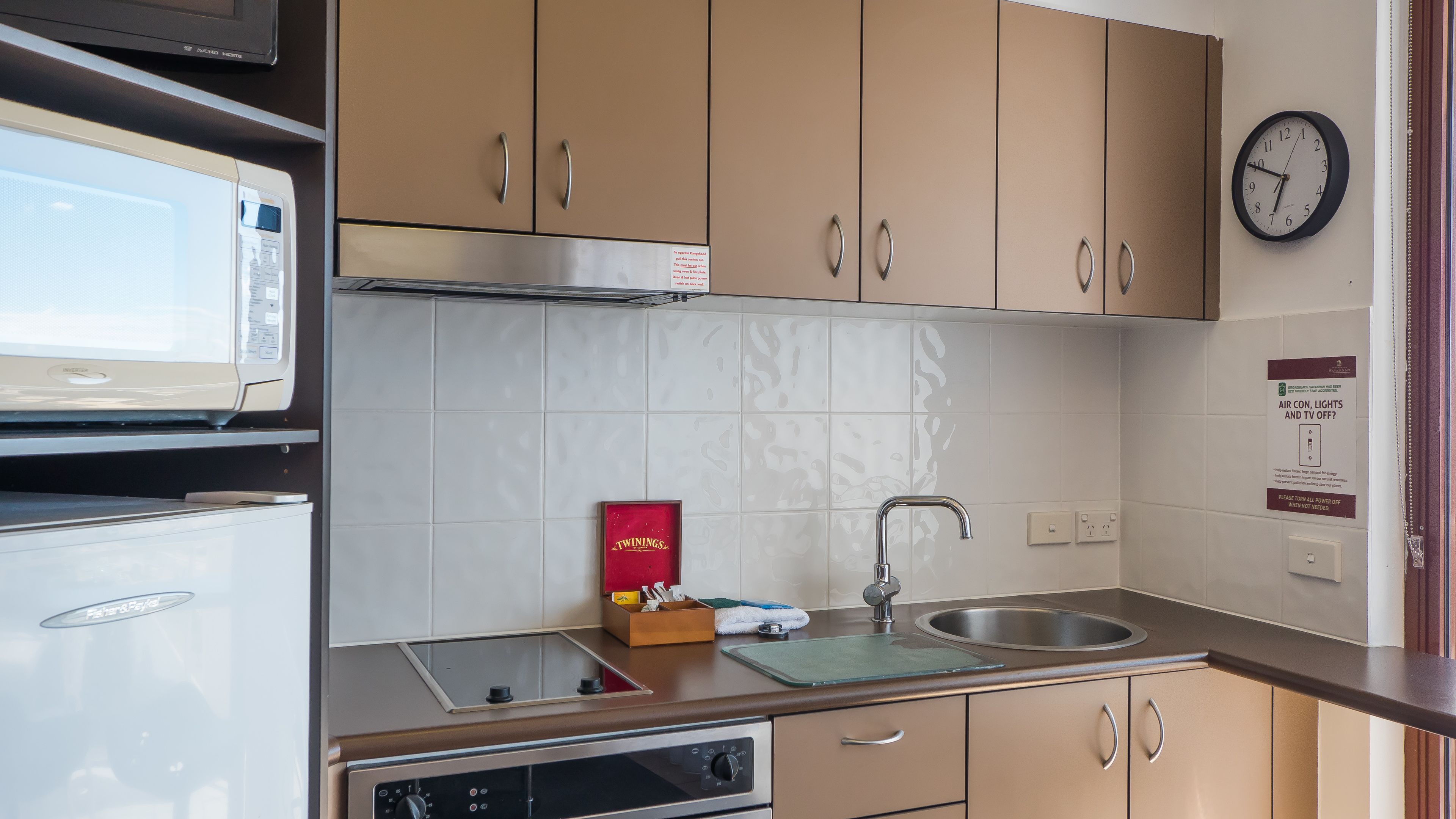 A compact kitchenette with a microwave, stove, sink, and cabinets.