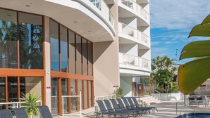 Un hôtel doté d’une piscine, de chaises longues et d’un bâtiment avec de nombreux balcons.