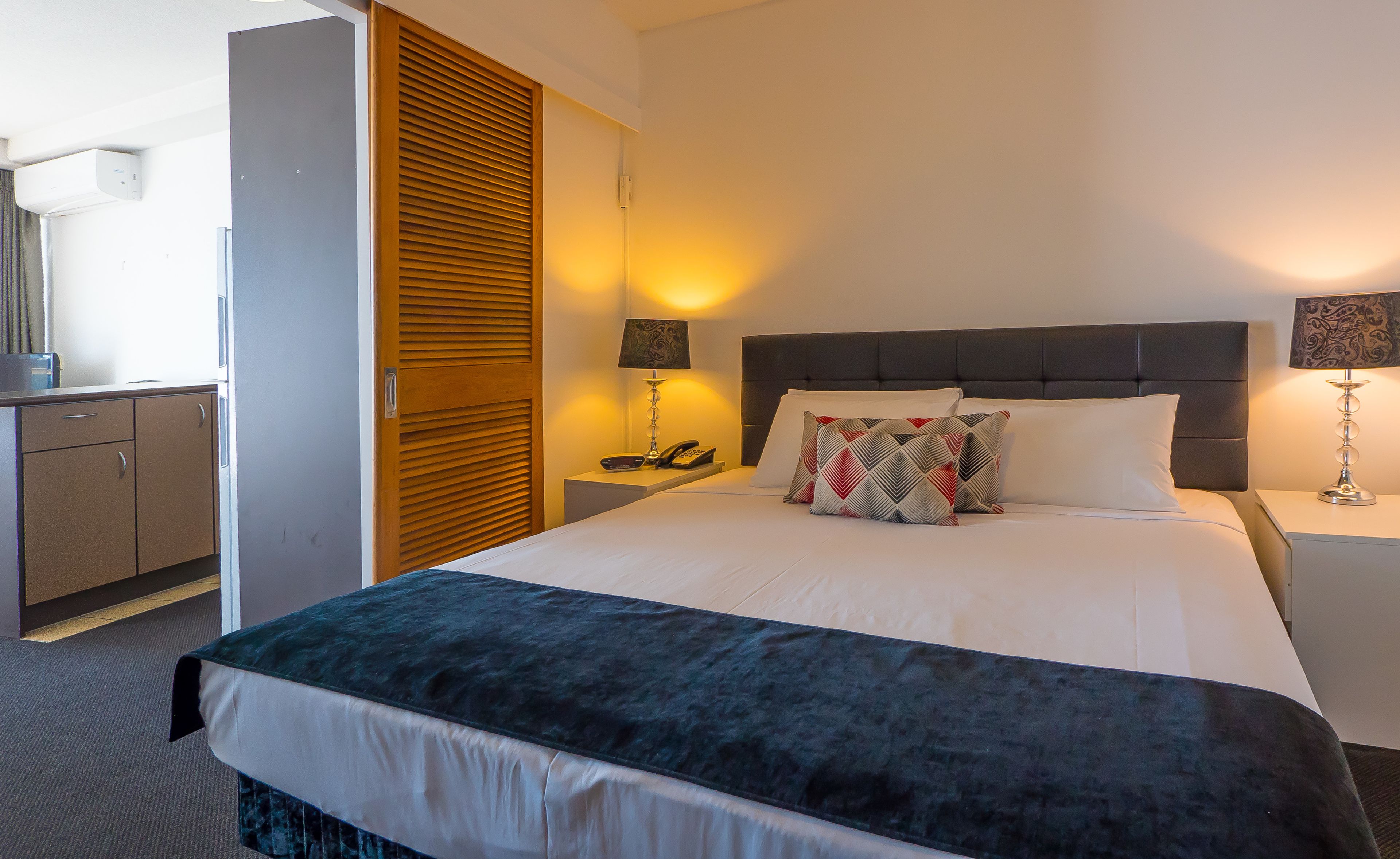 Una habitación de hotel con cama, mesitas de noche, escritorio y armario.