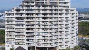 Un hôtel à plusieurs étages doté de balcons, d’une piscine et offrant une vue sur l’océan.