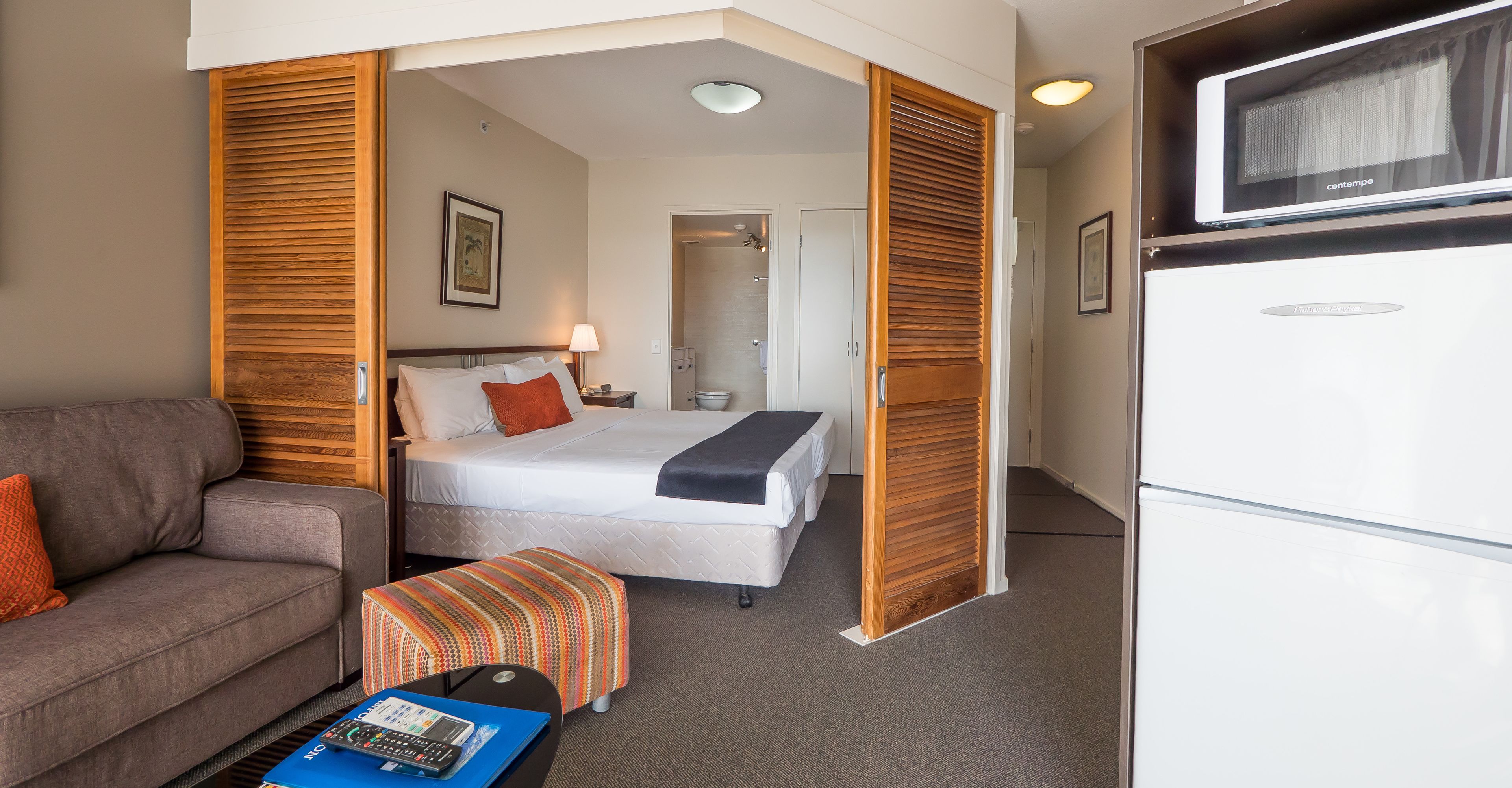 Une chambre d’hôtel équipée d’un lit, d’un canapé, d’un bureau avec un ordinateur portable, d’une télévision et d’un réfrigérateur.