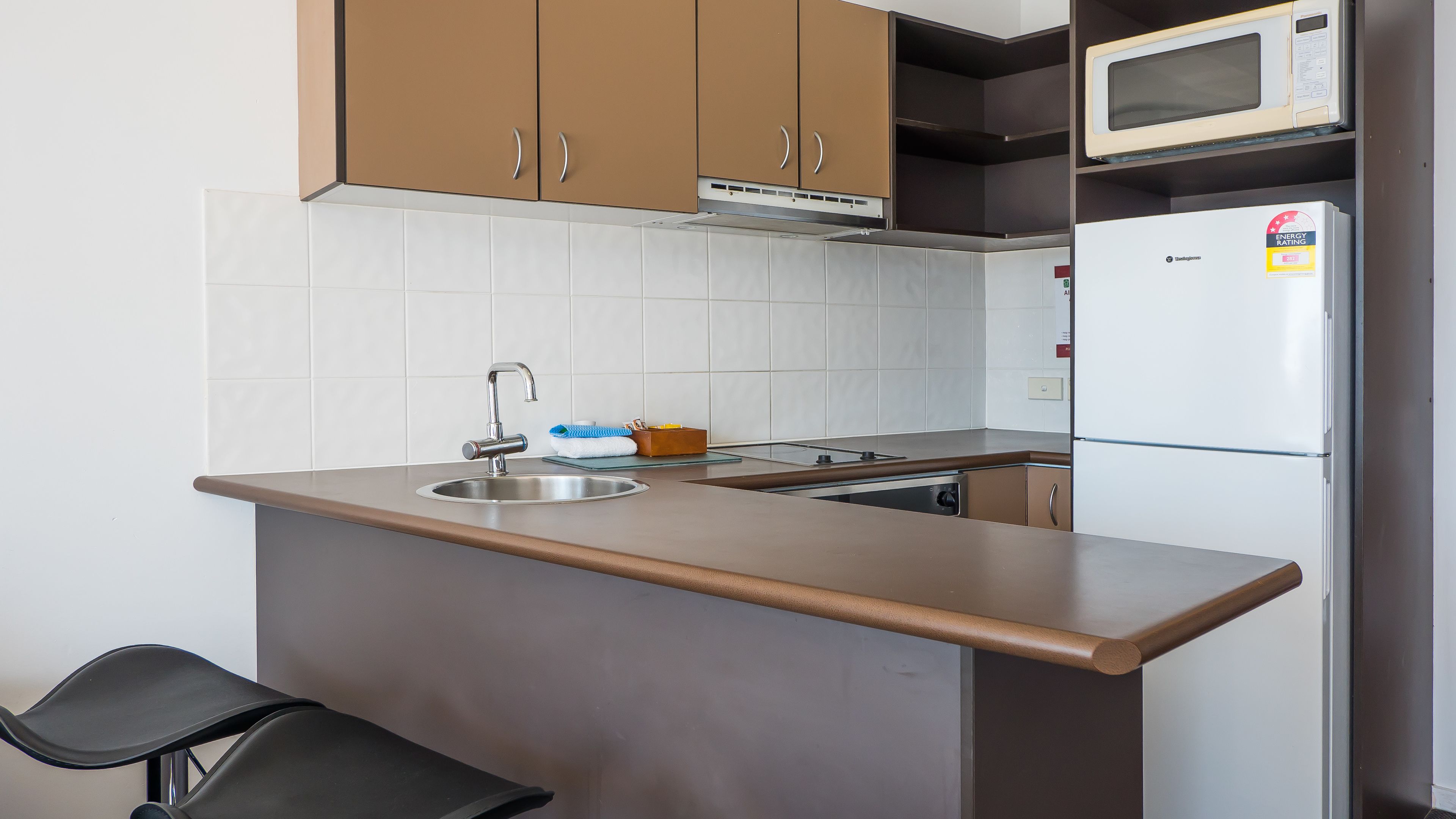 A compact kitchen with a sink, microwave, and refrigerator.