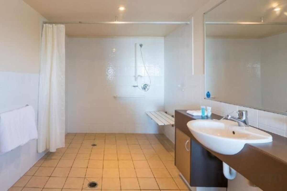 Un baño moderno con ducha, lavamanos y espejo.