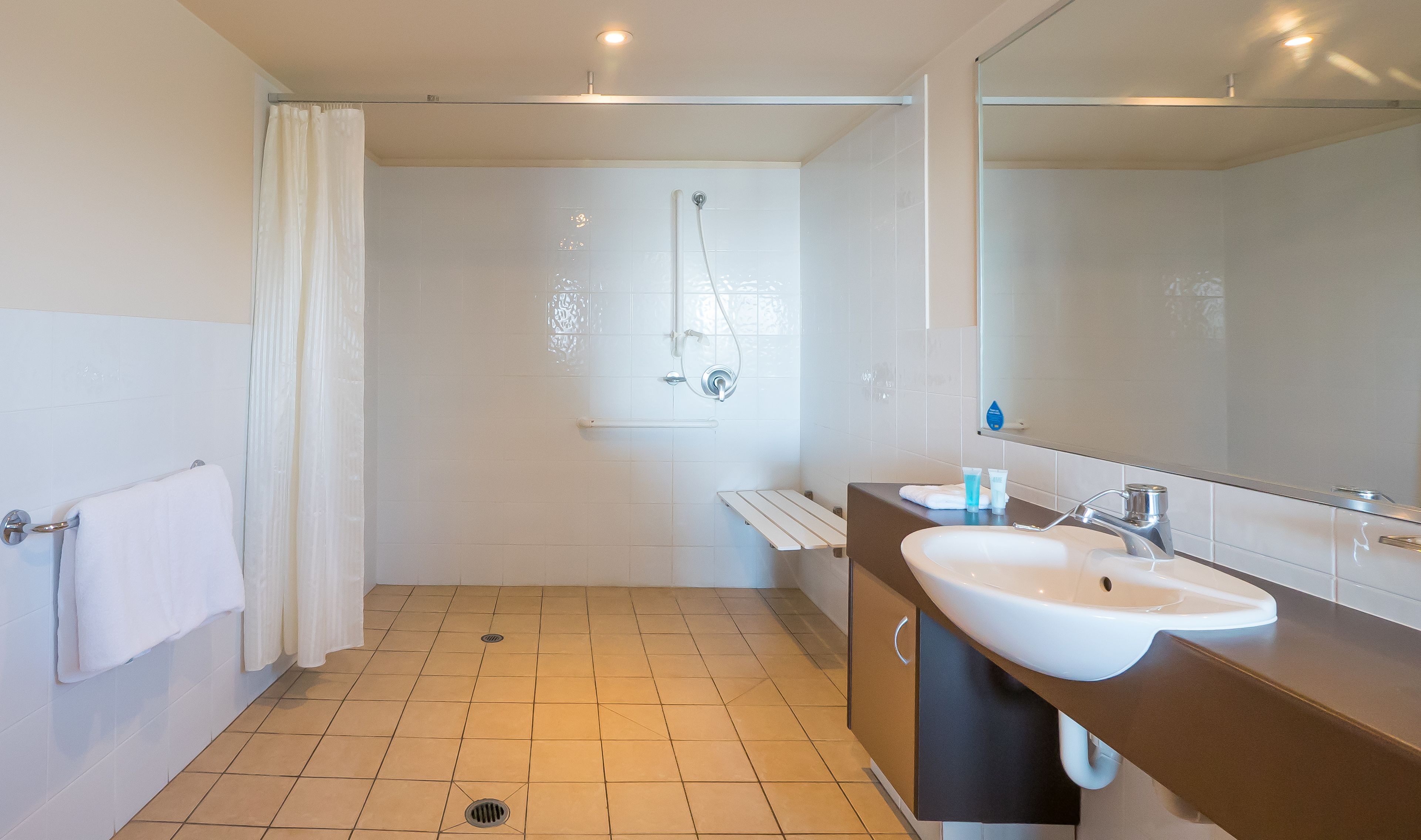 Un bagno moderno con doccia, lavandino e specchio.